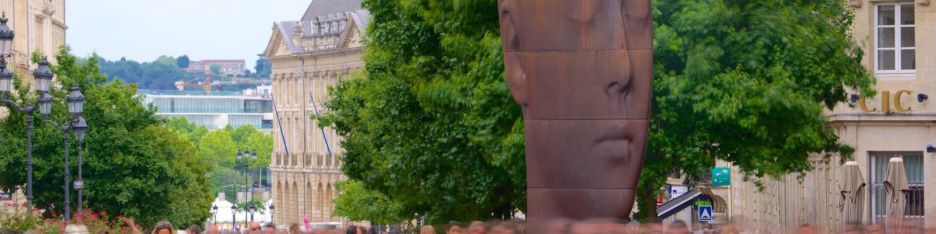 Una gran escultura de bronce en una plaza pública, con gente a su alrededor.