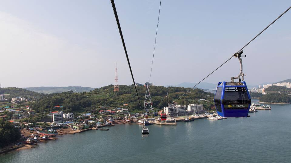 A cable car system over a body of water with a cityscape in the background.