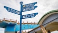 Un panneau de signalisation bleu indiquant plusieurs directions, notamment le port de pêche de Shuei, le centre d’accueil de Jinshan, le parc de Shitoushan et le centre-ville de Jinshan.