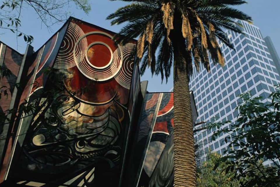 Un edificio con un gran mural de un dragón y una palmera.