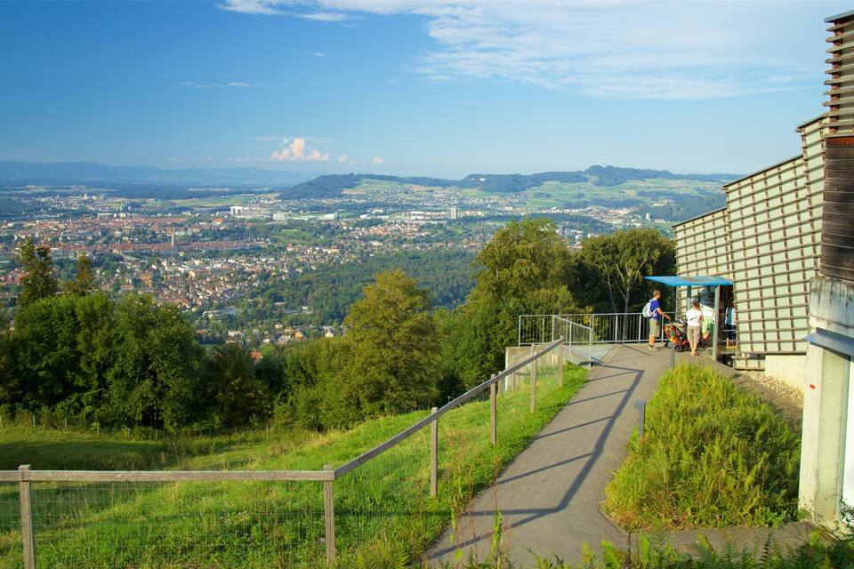 A scenic overlook with a pathway leading to a shelter, overlooking a town and distant mountains.