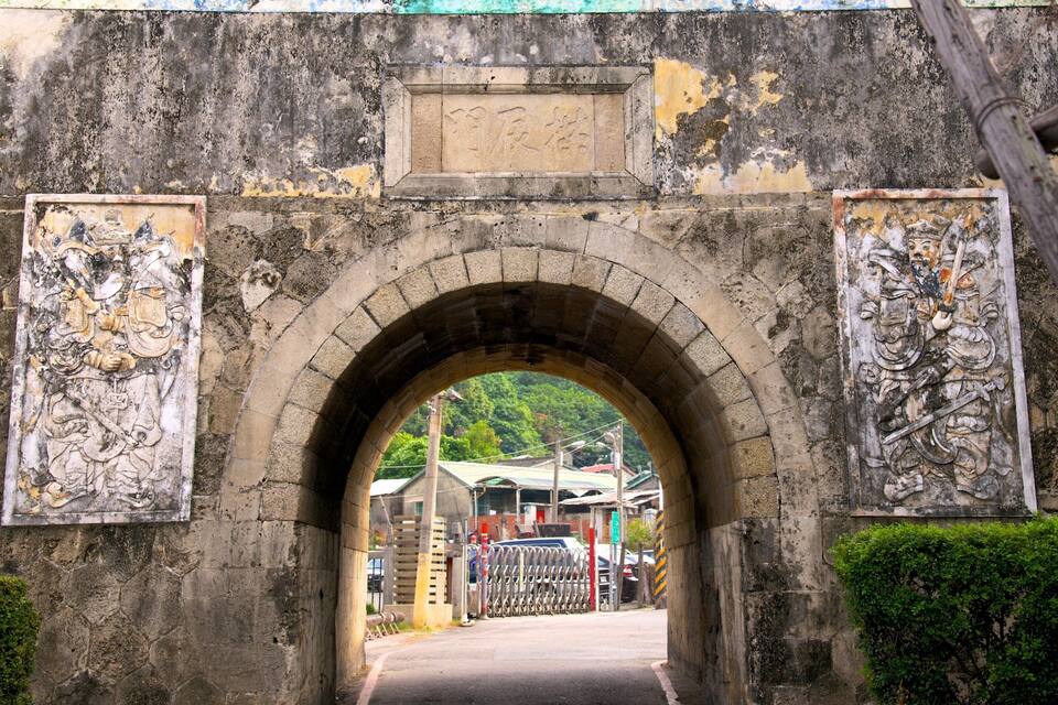 Un antiguo arco de piedra con adornos desgastados a ambos lados.