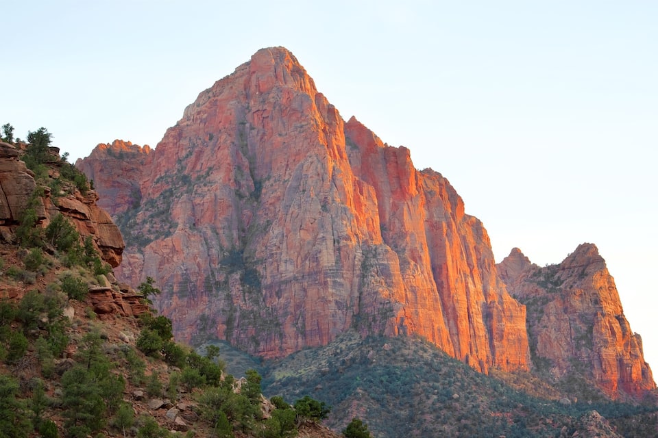 A rugged mountain range with prominent red rock formations and sparse vegetation.