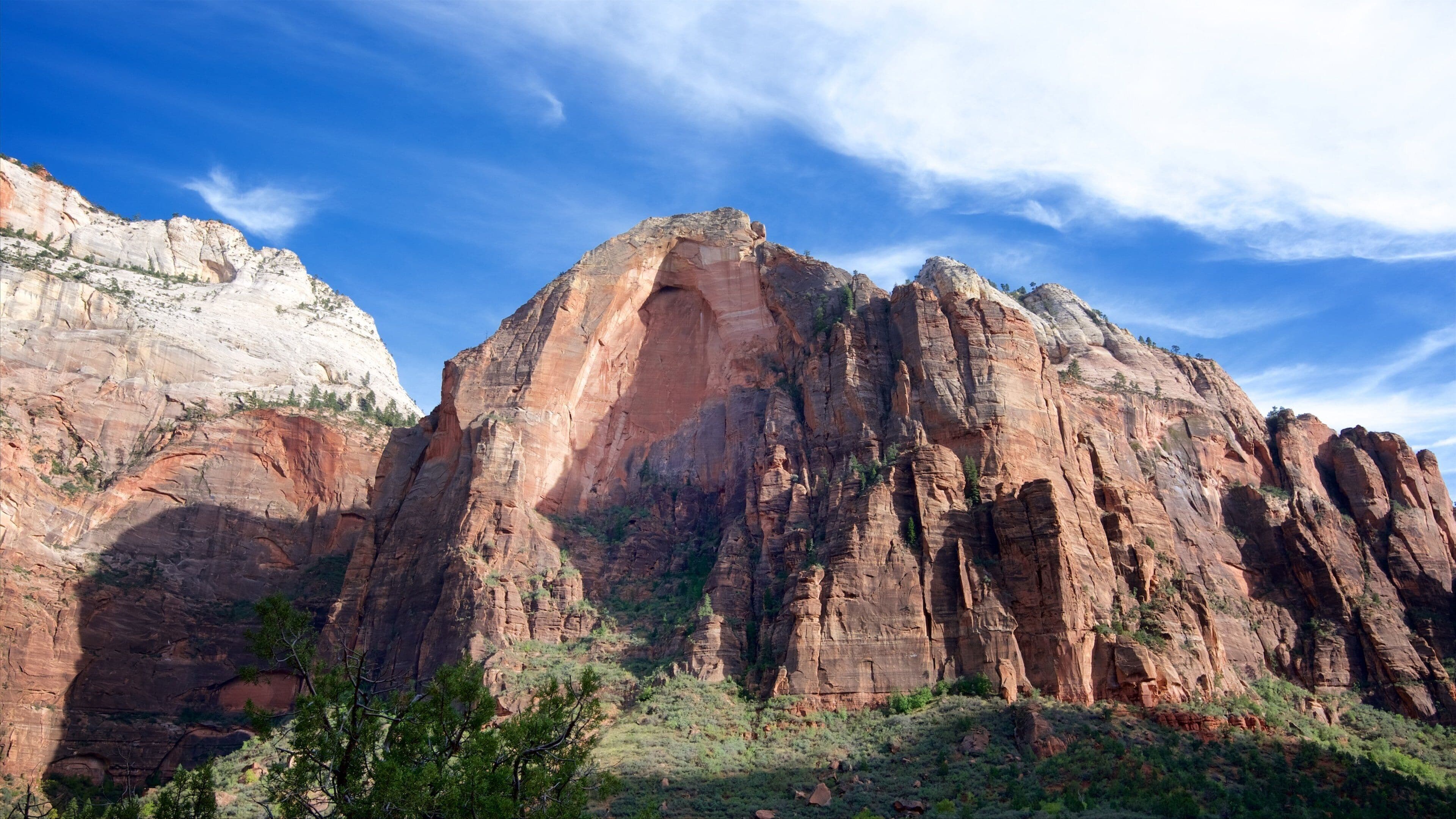 A large rock formation with a prominent arch and layered red and white rock faces.