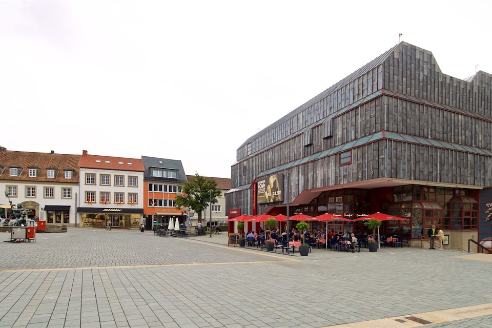 A cobblestone square with outdoor seating at a restaurant, surrounded by historic buildings.