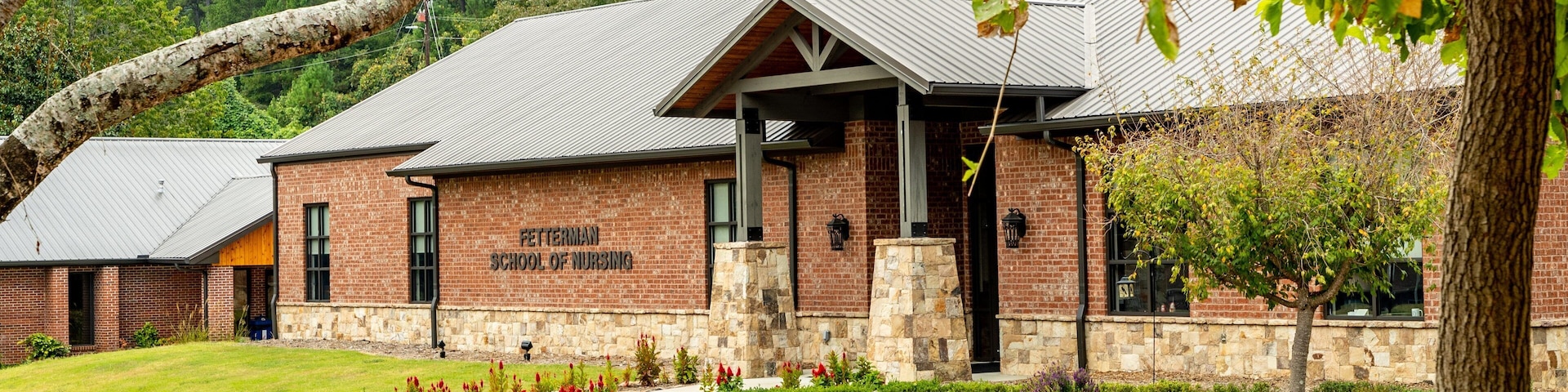 Um edifício de tijolos com telhado de metal, com a inscrição 'Fetterman School of Nursing'.