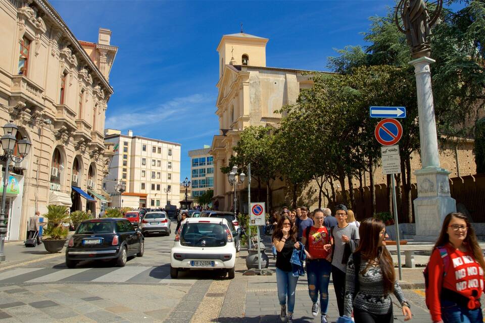 Ruas movimentadas da cidade com edifícios históricos, placa de proibido estacionar e pedestres.