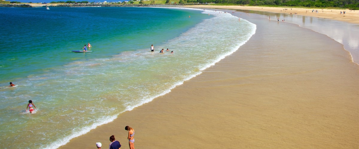 A beach with clear turquoise water, a sandy shore, and a few people in the water.