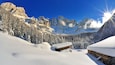Un paysage montagneux enneigé, avec des chalets en bois et un ciel bleu dégagé.