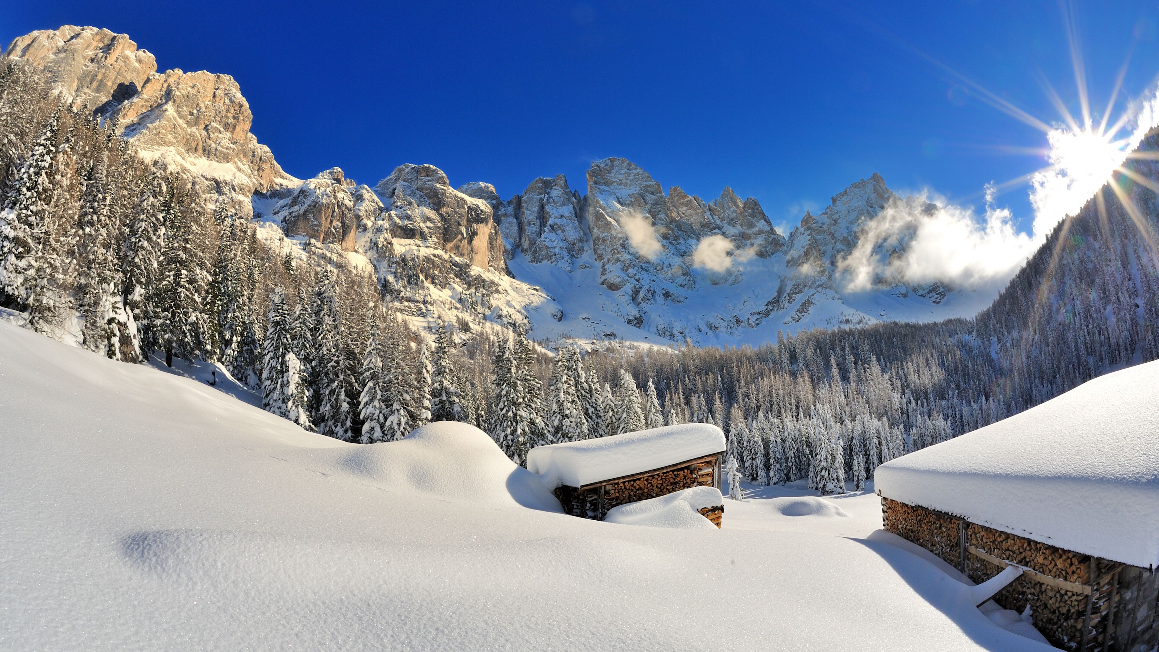 A snowy mountain landscape with wooden cabins and a clear blue sky.