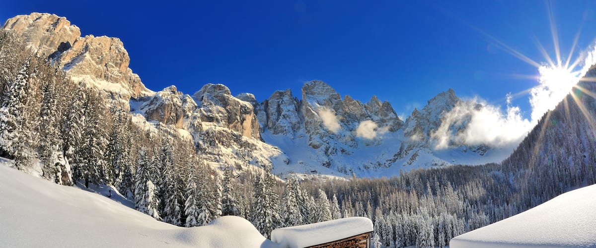 A snowy mountain landscape with wooden cabins and a clear blue sky.
