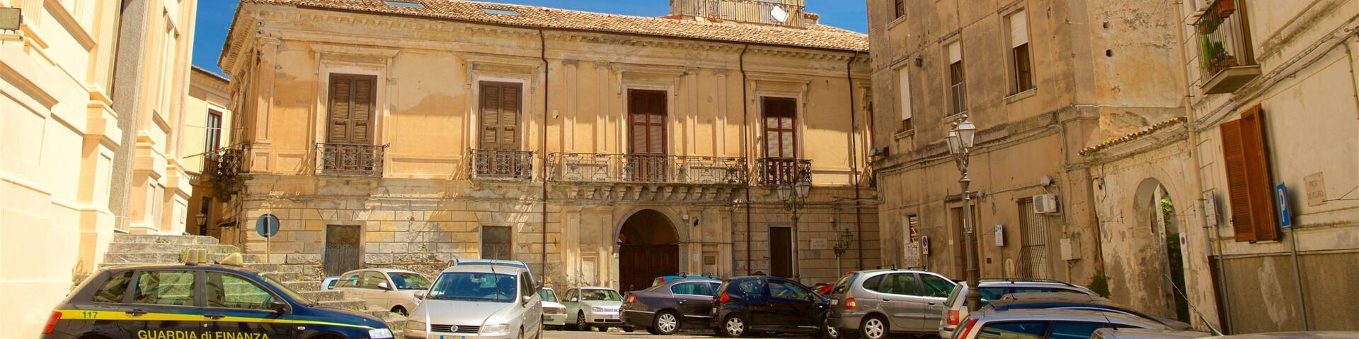 Una calle con coches aparcados y un edificio con cúpula y balcón.