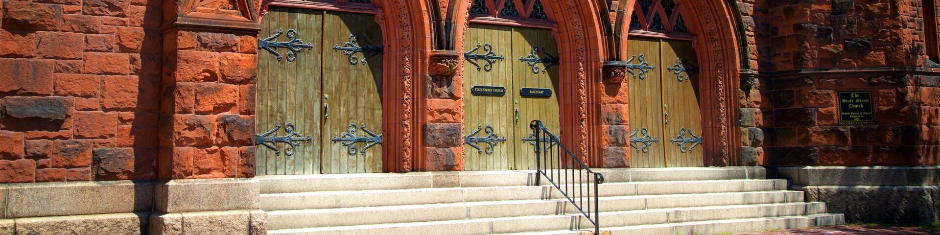 A red brick church with arched doors and a stone staircase leading up to the entrance.