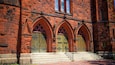 Una iglesia de ladrillo rojo con puertas en arco y una escalera de piedra que conduce a la entrada.