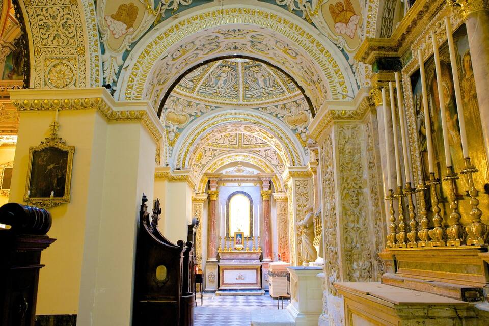 Ein kunstvoll gestalteter Kirchenraum mit detaillierten Fresken, einem großen Altar und einer Orgel.