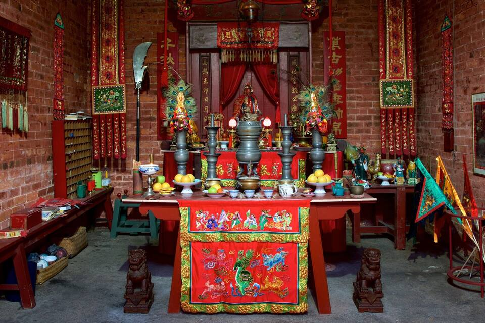 A traditional Chinese altar with incense burners, offerings, and colorful decorations.