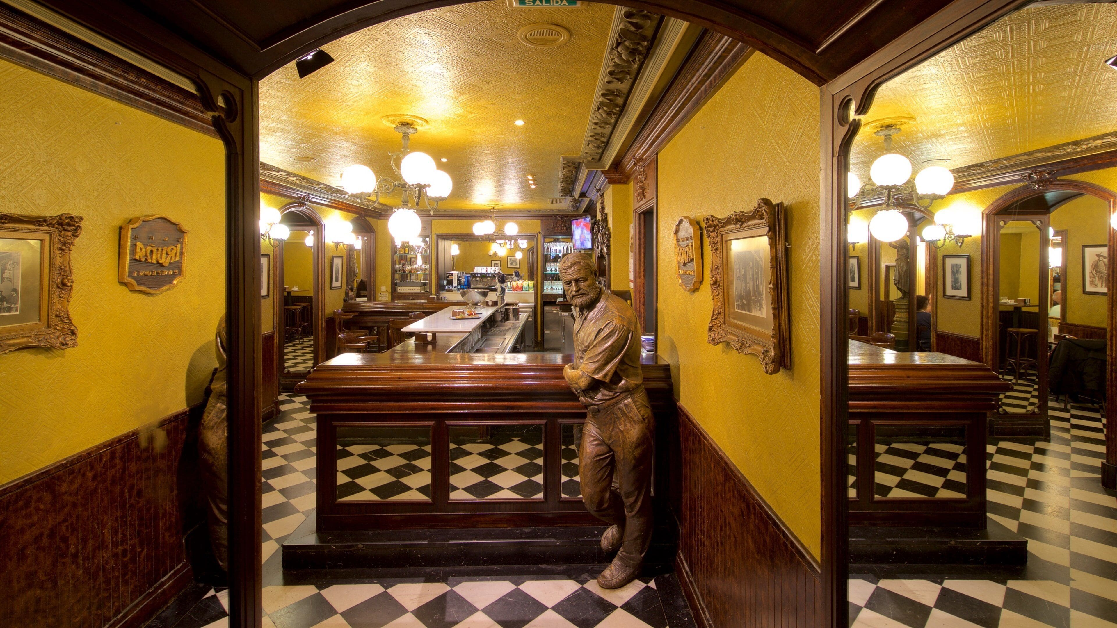 A restaurant interior with a checkered floor, wooden benches, and a statue of a man.