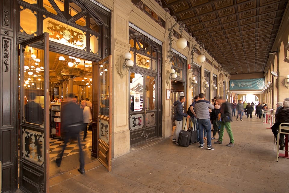 Une rue animée, bordée d’immeubles à l’architecture riche et agrémentée d’une galerie couverte.