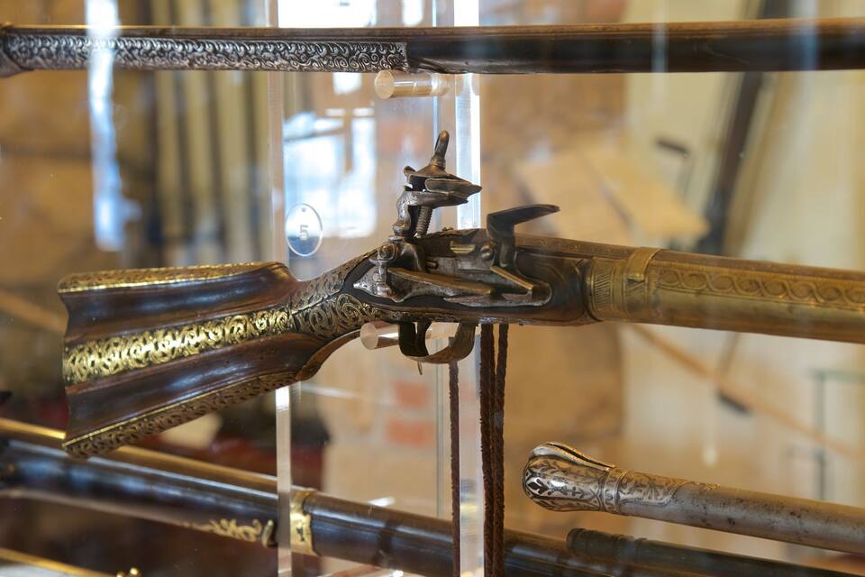 A collection of antique rifles displayed in a glass case.