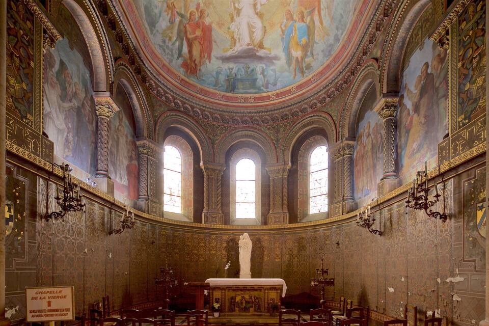 Interior ornamentado de una capilla con una estatua central, ventanas en arco y frescos detallados en el techo.