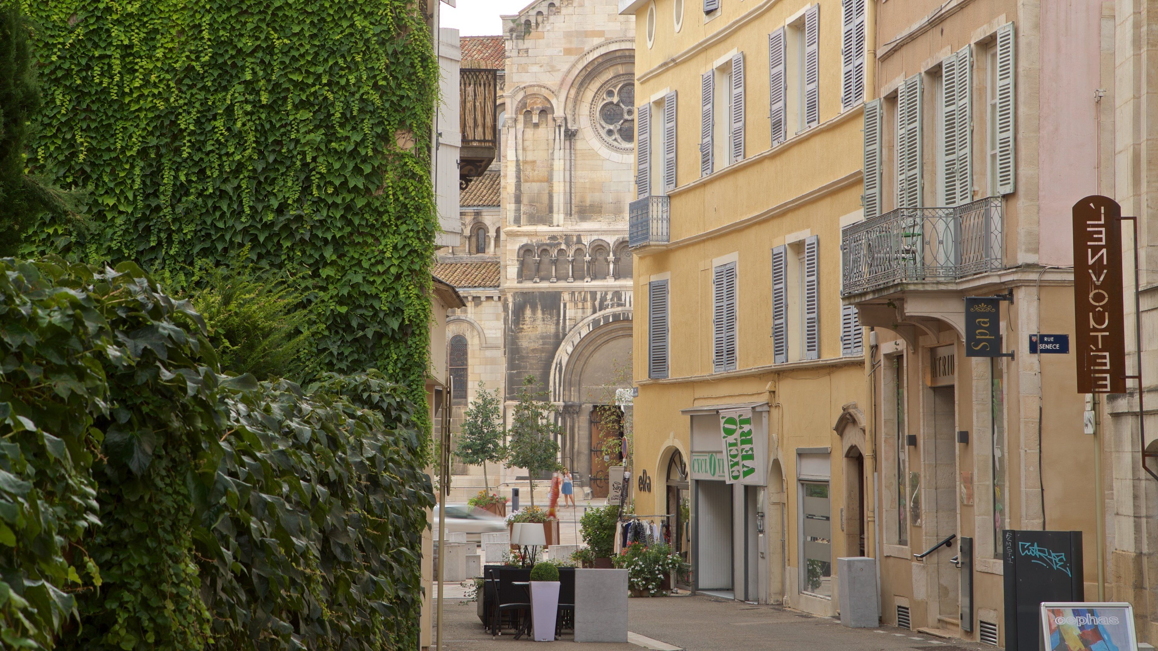 A narrow street lined with historic buildings, a café, and a sign for a spa.
