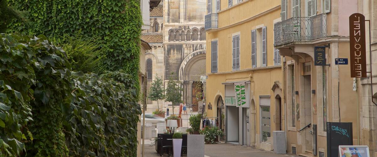 A narrow street lined with historic buildings, a café, and a sign for a spa.