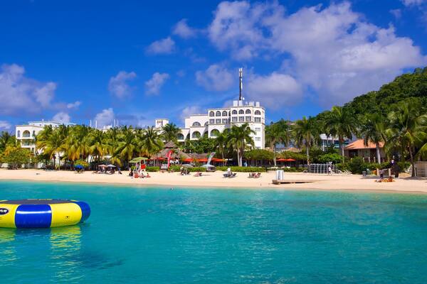 Doctor\'s Cave Beach mostrando una playa de arena, una ciudad costera y escenas tropicales