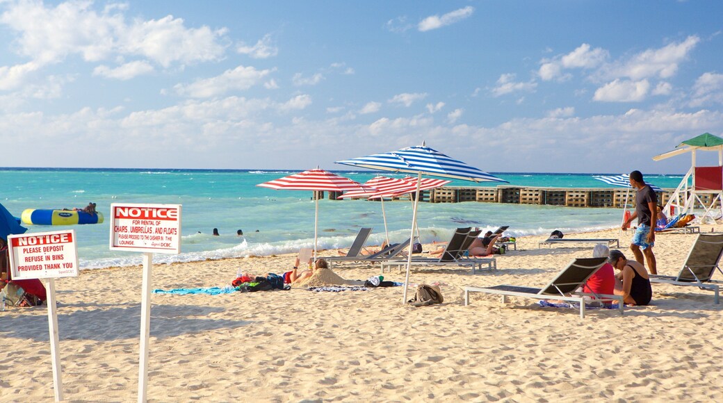 Doctor\'s Cave Beach showing signage and a sandy beach as well as a small group of people