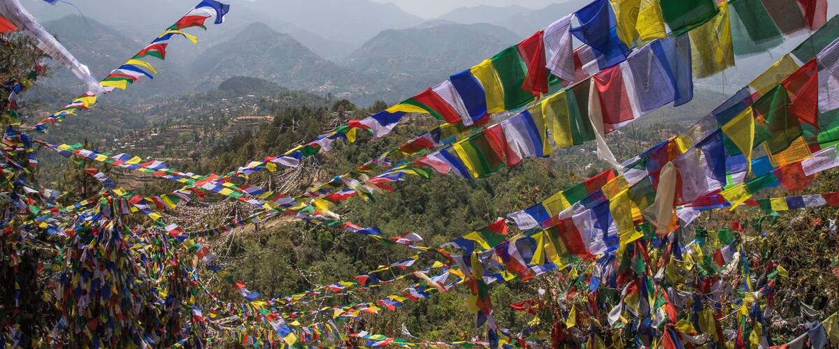Colorful prayer flags strung across a mountainous landscape.