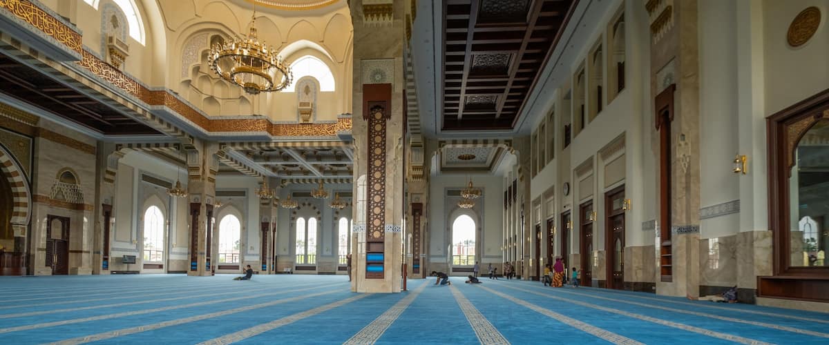 Un grand hall doté d’un tapis bleu, de colonnes richement décorées et de lustres.