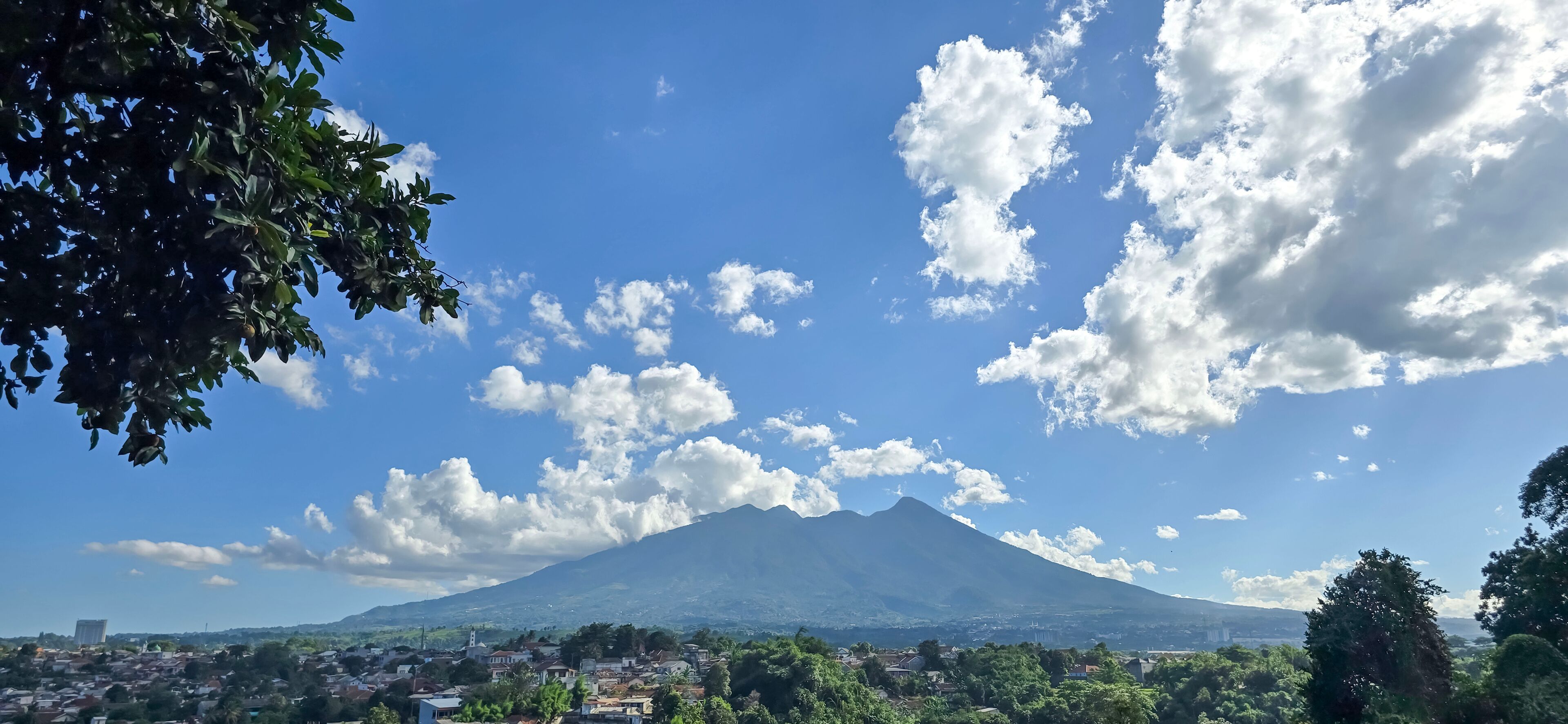 A mountain with a clear sky and scattered clouds.