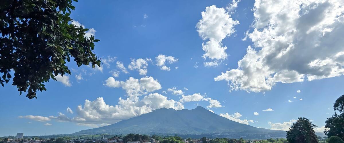 A mountain with a clear sky and scattered clouds.