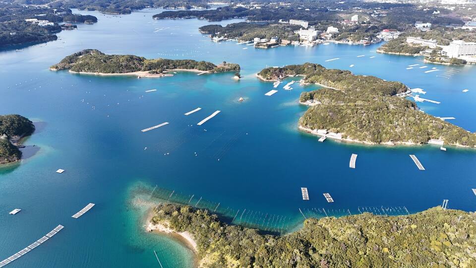 An aerial view of a coastal area with multiple islands, clear blue waters, and several piers.