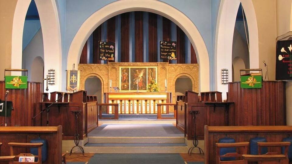 An interior of a church with wooden pews, a pulpit, and a large altar.