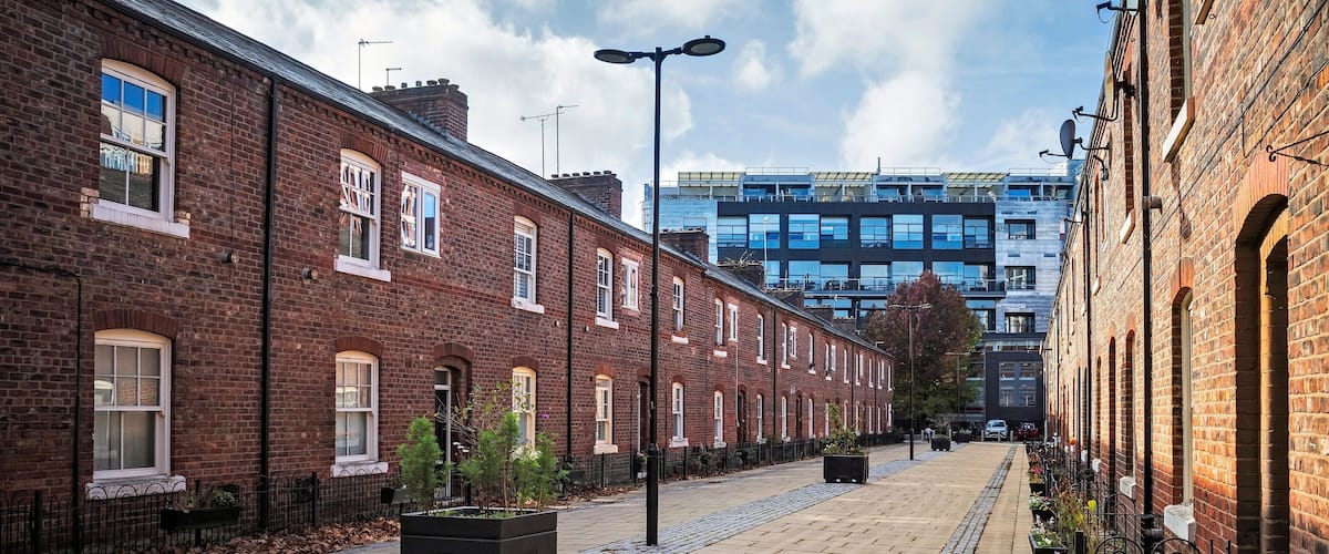 A brick-lined street with a cobblestone path, a modern building in the background, and a clear sky.