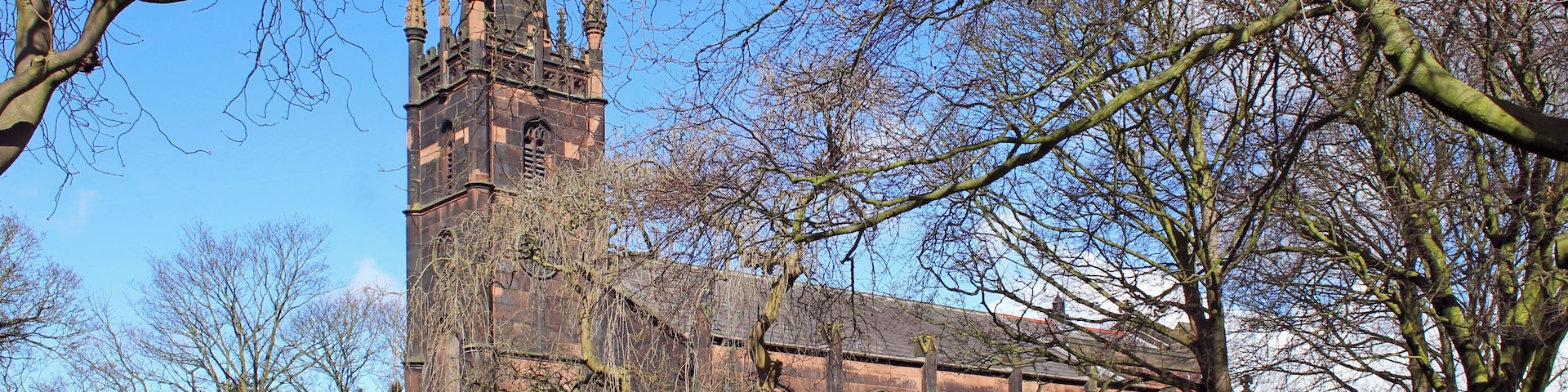 Grade II listed stone church in Knotty Ash, Liverpool, dating to 1835 with chancel and side chapel added 1890. in mixed, but compatible styles by Aldridge & Deacon.Seen from Brookside Avenue near junction with Thomas Lane.