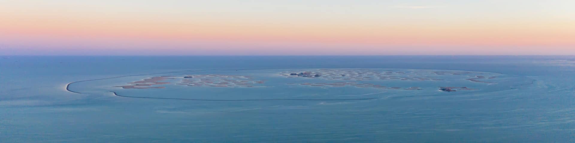 Aerial view of The World Islands on Dubai sea with sunset sky, United Arab Emirates or UAE. Architecture landscape background with sky.
