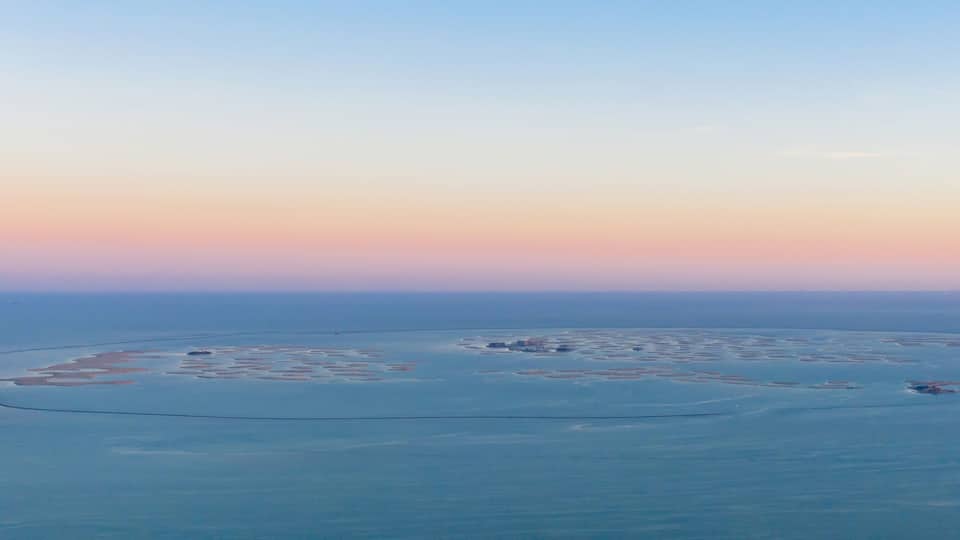 Aerial view of The World Islands on Dubai sea with sunset sky, United Arab Emirates or UAE. Architecture landscape background with sky.