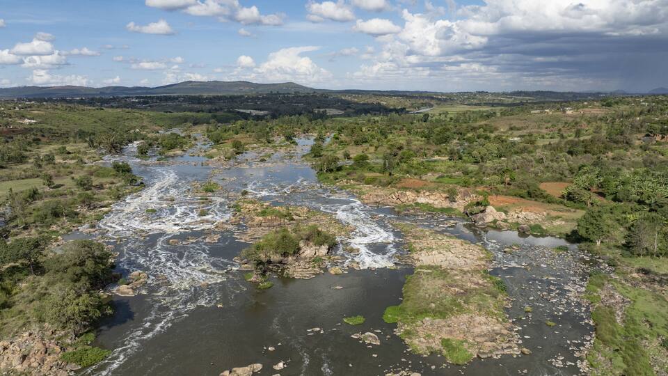 A river winding through a green landscape with hills in the background.