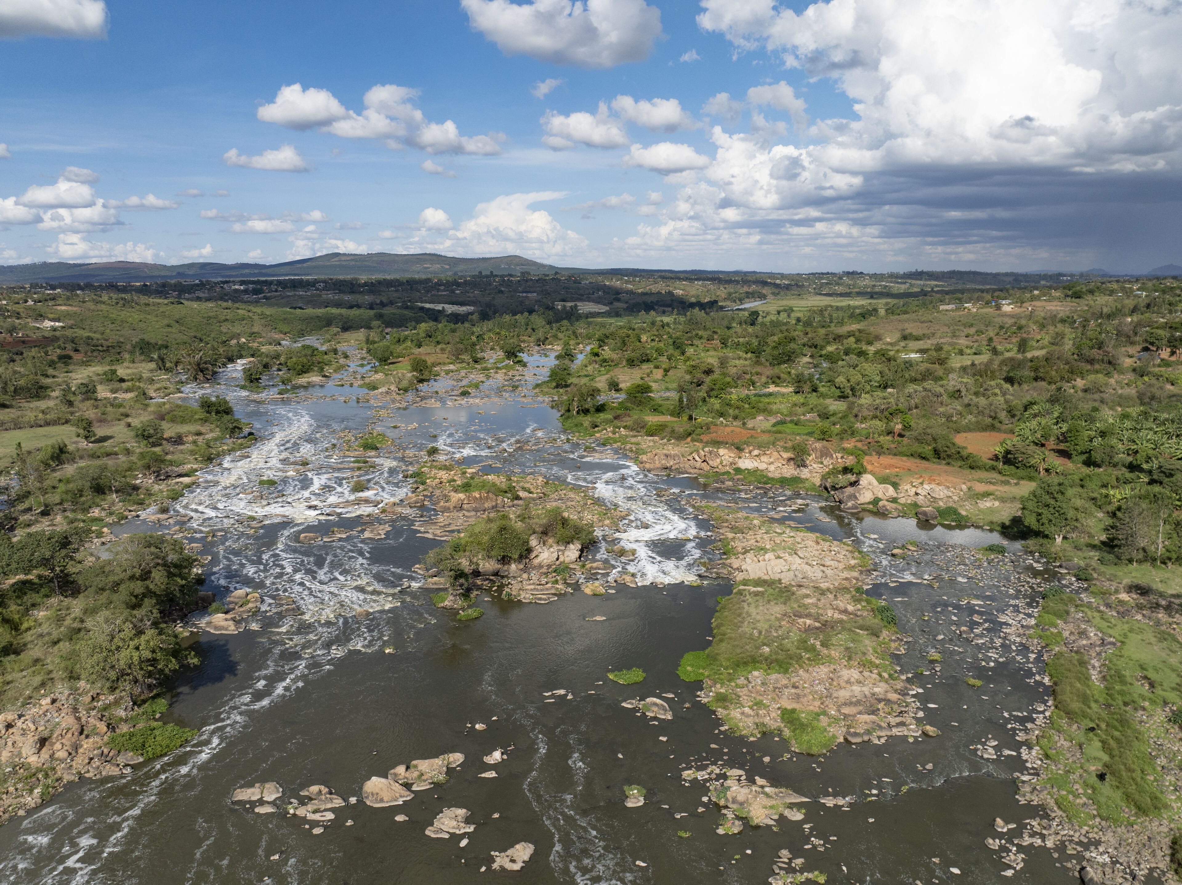 A river winding through a green landscape with hills in the background.