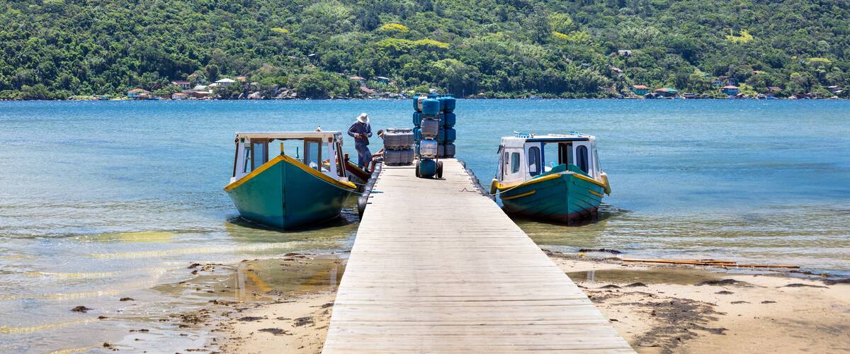 A wooden pier extending into a calm lake with boats docked at both ends.