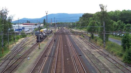 Un nudo ferroviario con múltiples vías y un paisaje montañoso de fondo.