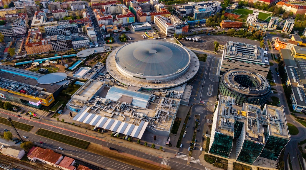 Cheskomoravska, Czechia - 21 April 2026: Aerial view of O2 arena surrounded by modern office buildings and residential blocks under clear sunlight.