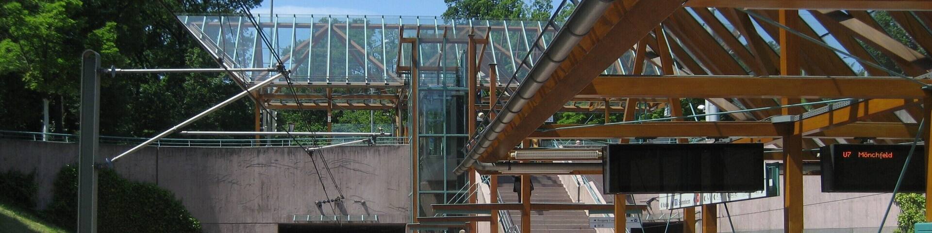 A modern train station with a glass bridge, a platform, and a tunnel entrance.