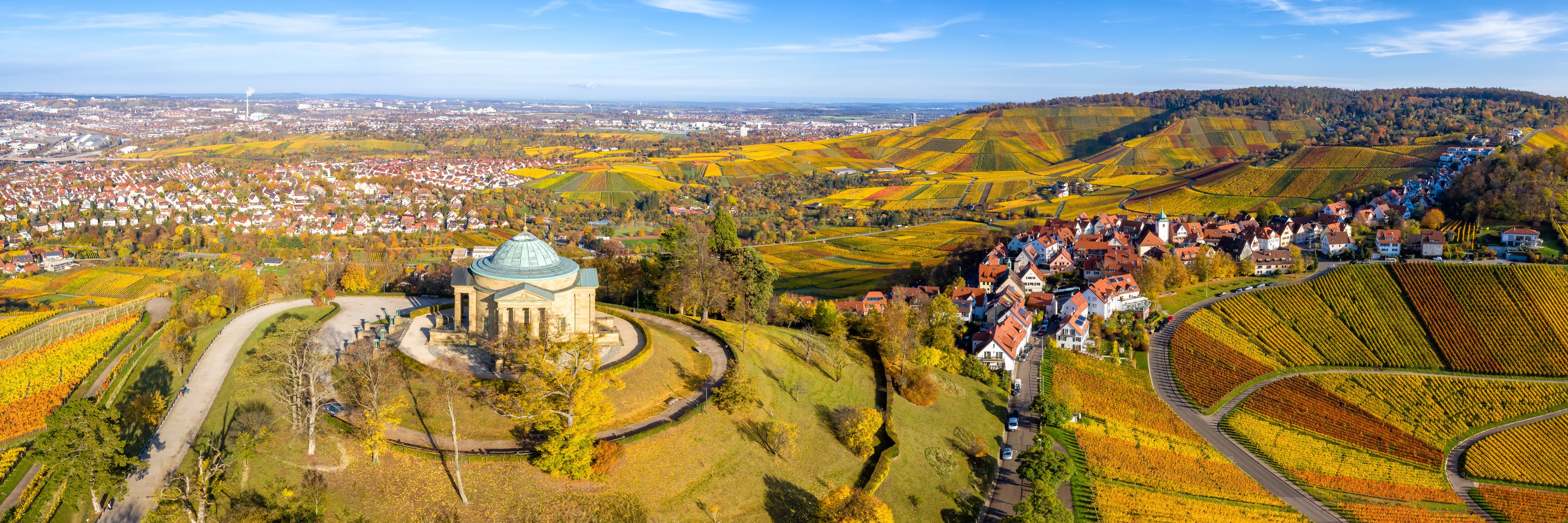 Vista panorámica de un pueblo con una iglesia destacada, colinas ondulantes y campos de cultivo.