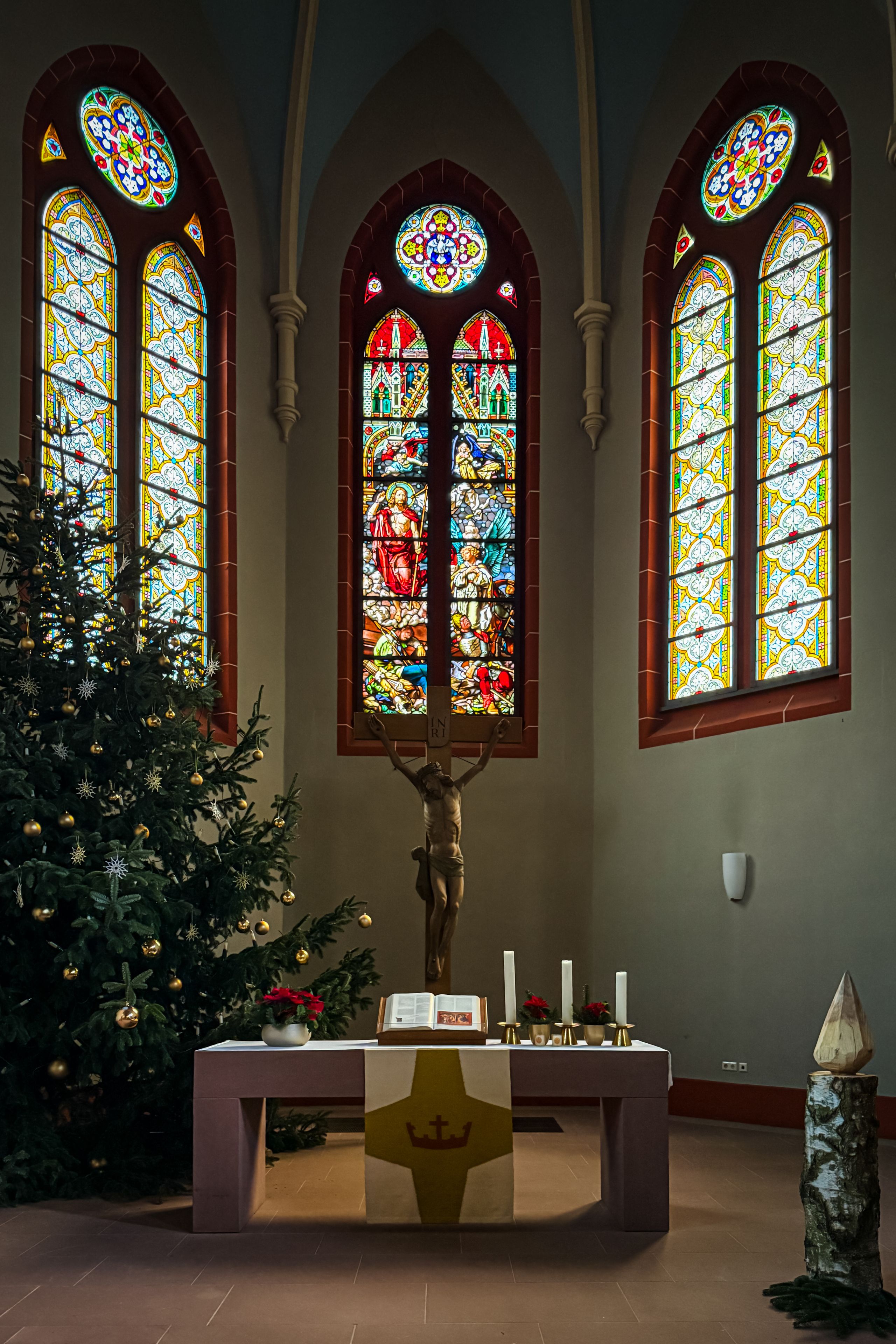 A church interior with stained glass windows and a Christmas tree.