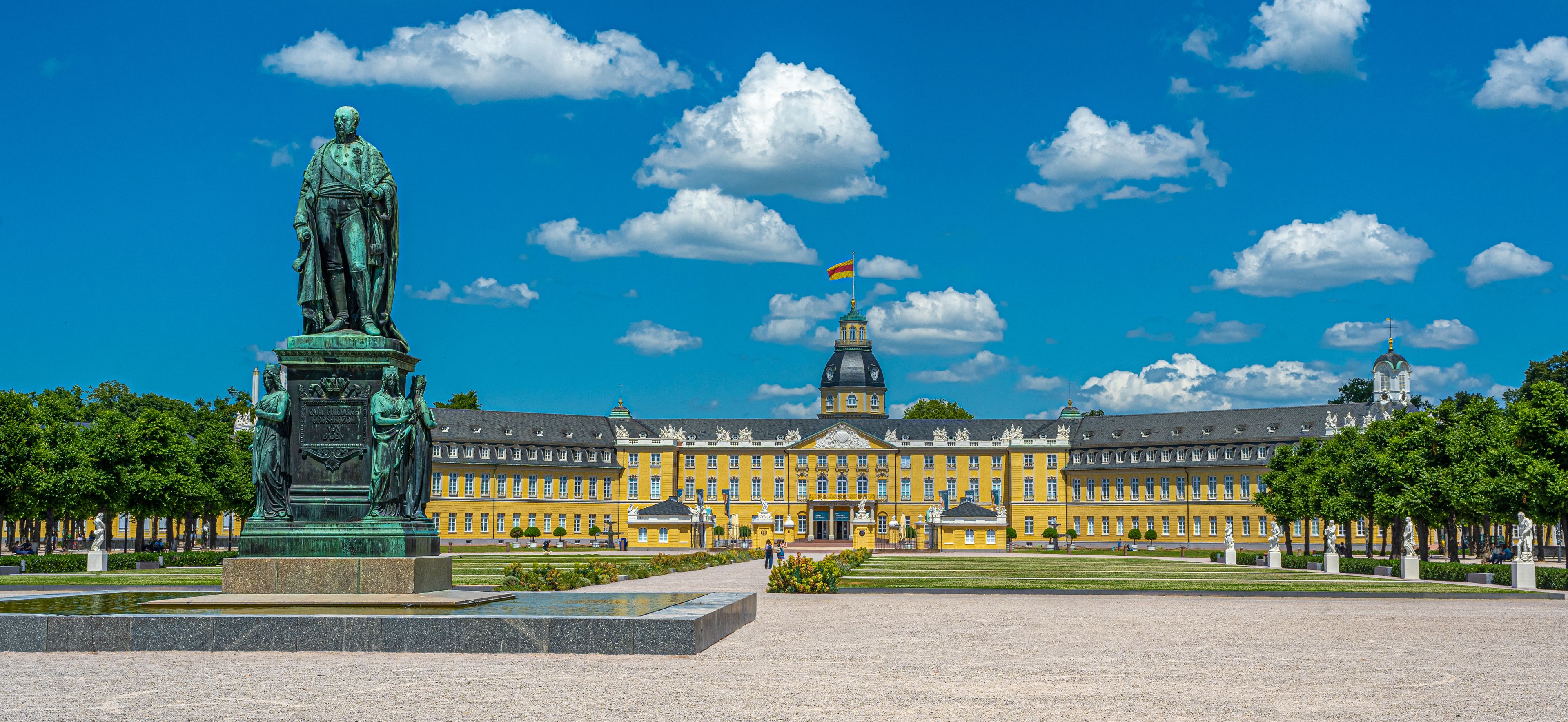 A large yellow building with a statue in front.