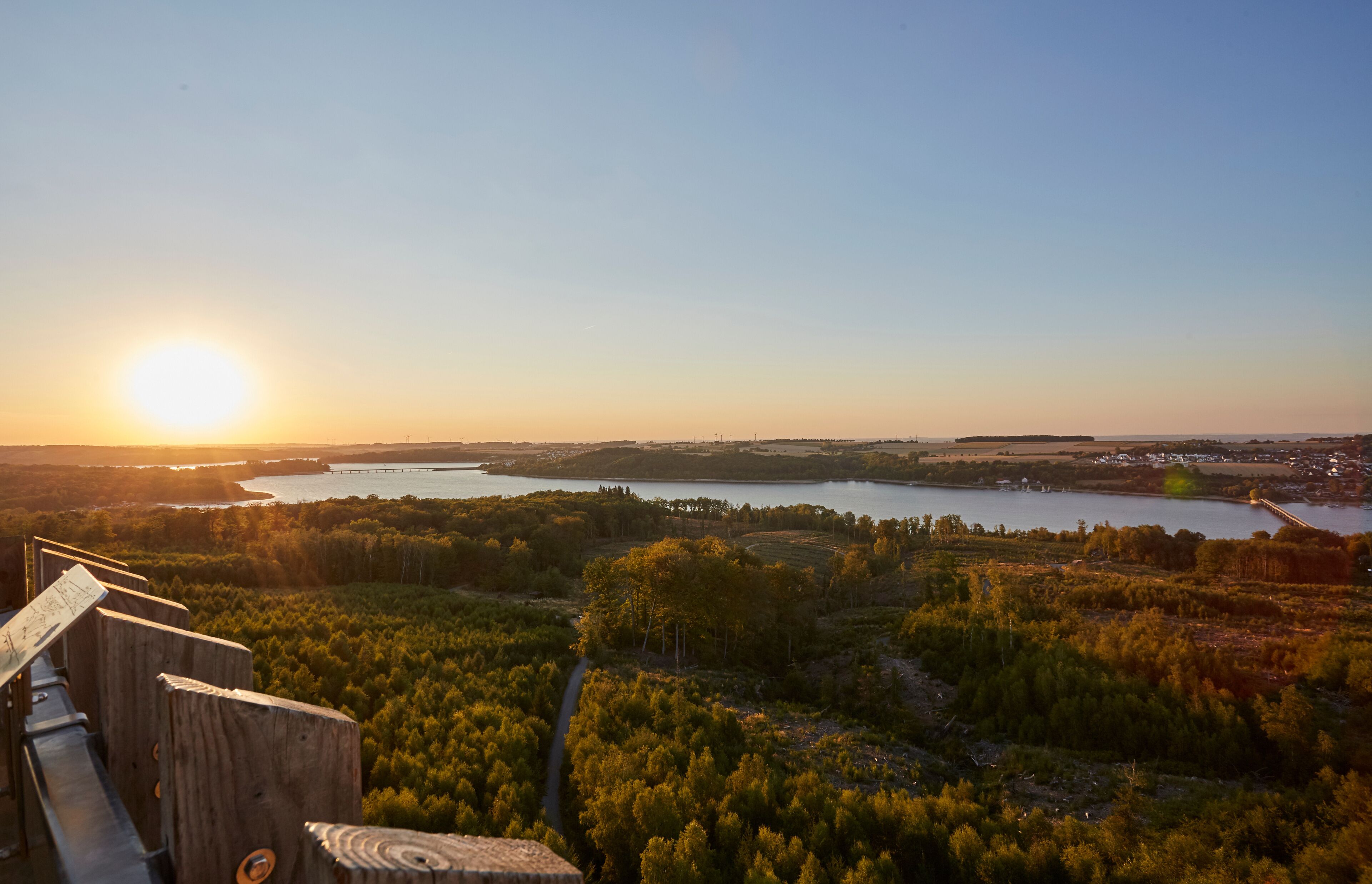 A sunset over a lake with a wooden viewing platform in the foreground.