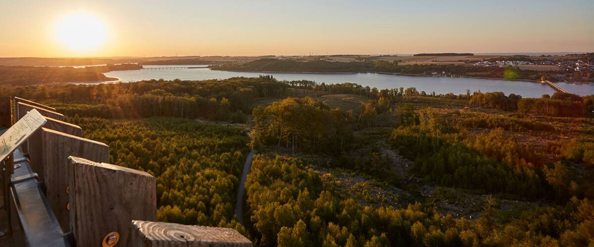 A sunset over a lake with a wooden viewing platform in the foreground.