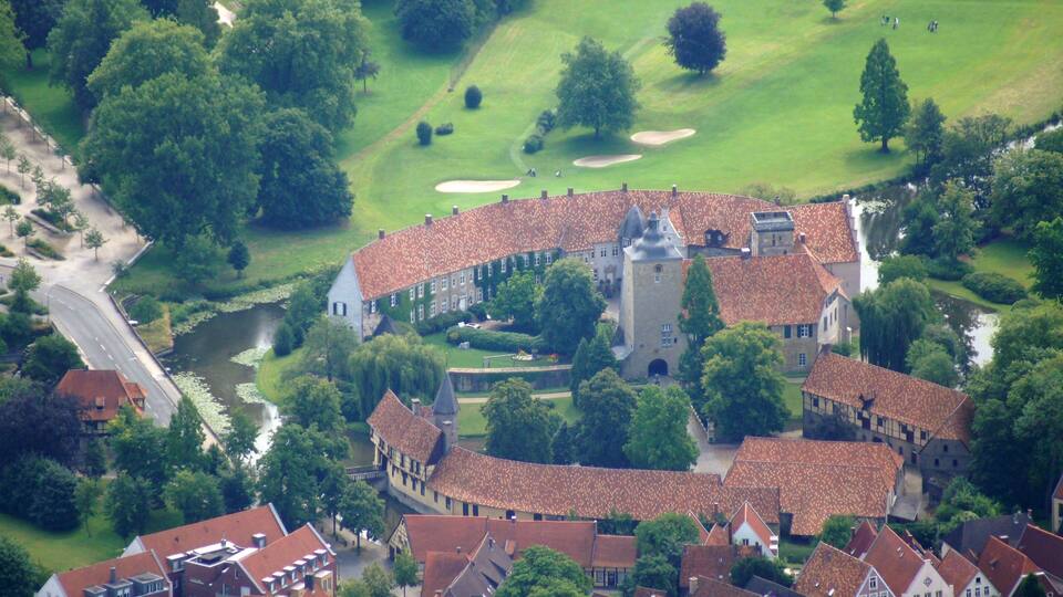A historic town with a castle, a golf course, and a river.